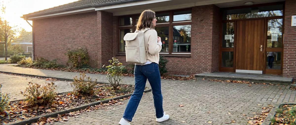 Lehrerin trägt den cremefarbenen Everyday Backpack Rucksack vor einer Schultafel