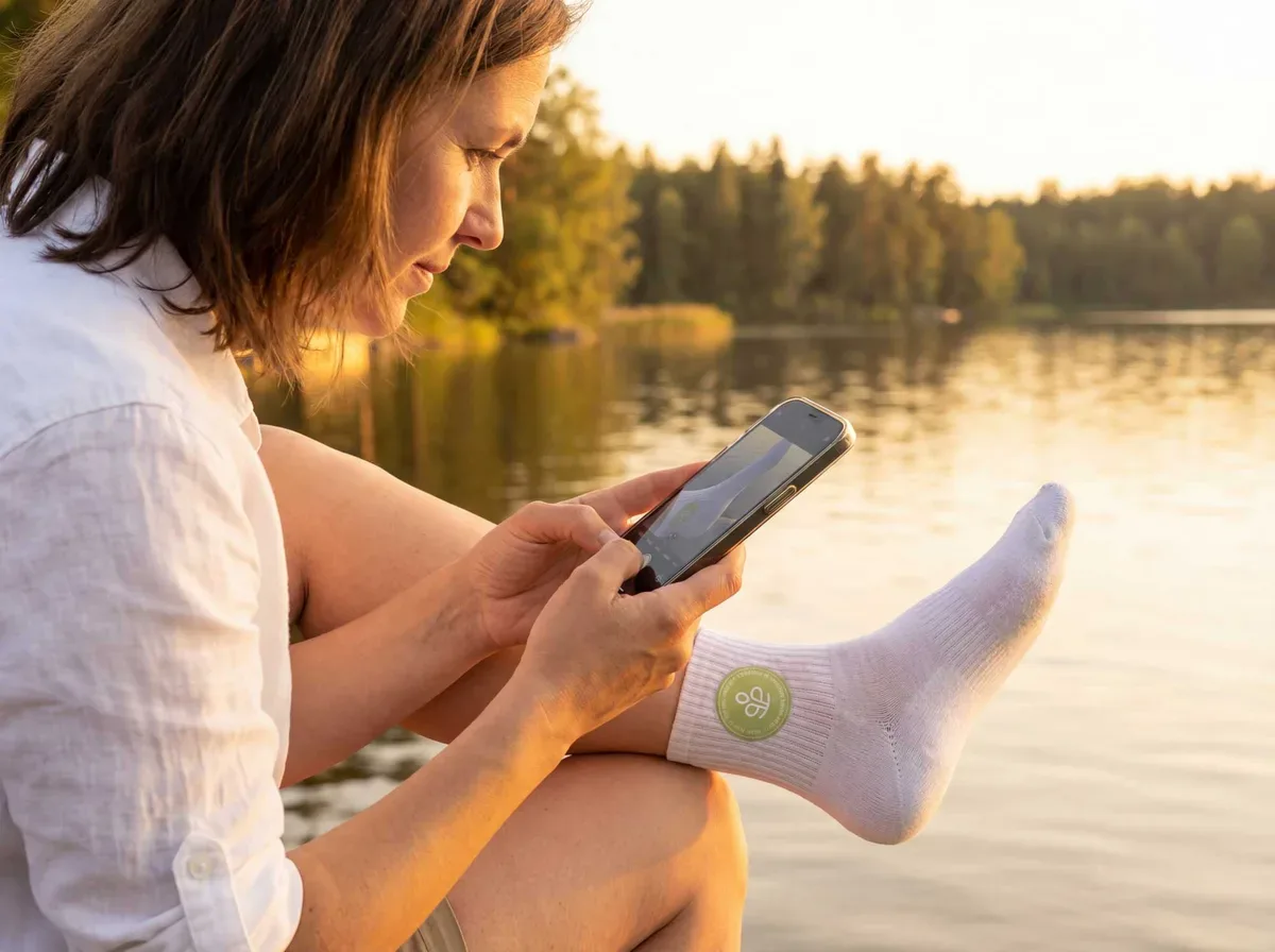 Happy family of four sitting around campfire at dusk without mosquito concerns, children roasting marshmallows while parents relax in camping chairs, soft lantern lighting with lake and trees in background